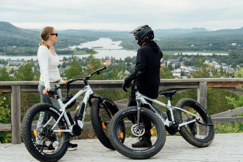 a man and a woman standing next to their bikes at Grand Arctic Resort in Överkalix