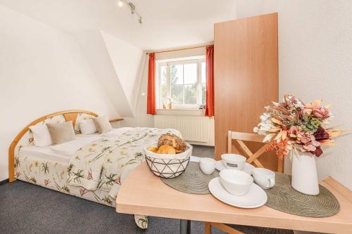 a bedroom with a bed and a table with plates and cups at Ostseeglück App Mittagsonne in Loddin