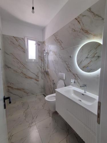 a bathroom with a sink and a toilet and a mirror at Sunset Bliss Apartments in Sarandë