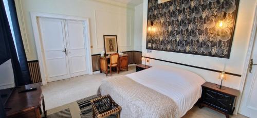a bedroom with a bed and a large painting on the wall at Suite Millésime du Château - Proche Océan in Gaillan-en-Médoc
