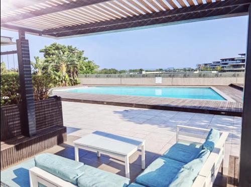 a patio with a couch and a table and a pool at Luxury Coastal Escape Coral Point Sibaya Pool & WiFi in Durban