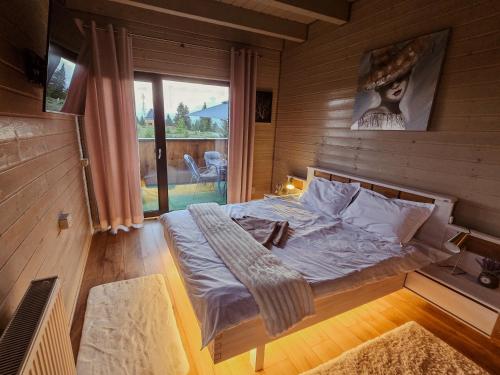 a bedroom with a bed and a large window at Belis Chalet in Bălceşti