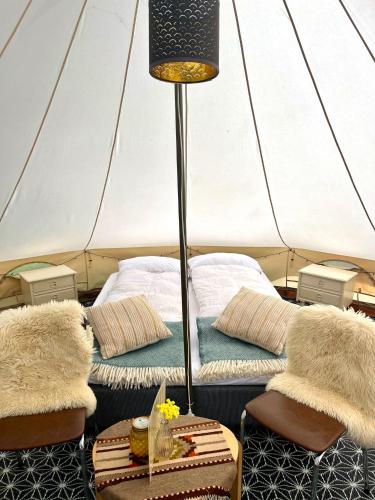 a bed and two chairs in a tent at Lystang Camping & Cabins in Notodden