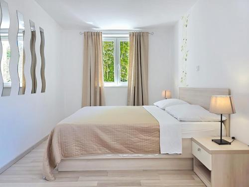 a white bedroom with a bed and a window at Apartments Gorica 2 in Baška