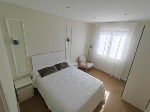 a white bedroom with a bed and a window at El Sol de la Paz in Haro