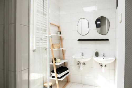 a white bathroom with two sinks and a shower at Nowoczesny Apartament Prudnik in Prudnik