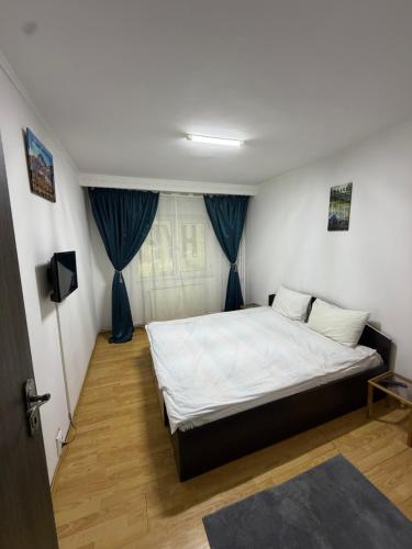 a bedroom with a large bed with blue curtains at Hypnotic Suite 1 in Piteşti