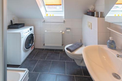 a bathroom with a toilet and a sink and a washing machine at Exklusive Ferienwohnung Sonnenplatz 30 in Norddeich