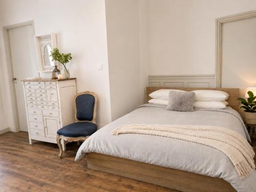 a bedroom with a bed and a blue chair at Fontaine Studio Appartement in Ribérac