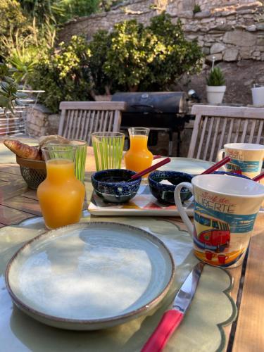 a table with a plate and some cups and juice at Di colombie in Figari