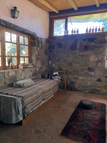 a bedroom with a bed and a stone wall at Refugio La Paciencia in Travesía