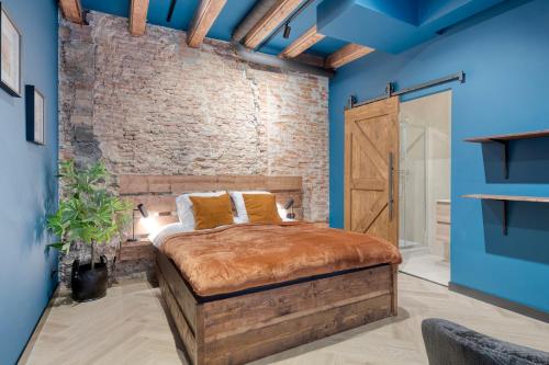 a bedroom with a bed with blue walls and a brick wall at Boutique Hotel Alkmaar - City Rooms & Apartments in Alkmaar