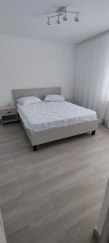 a white bedroom with a bed and a wooden floor at Apartament Bianco in Brăila