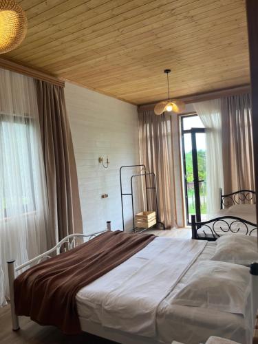 a bedroom with a large bed with a wooden ceiling at Balda Novel House in Martvili