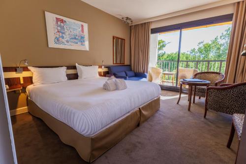 a hotel room with a large bed and a balcony at Villa Borghese, The Originals Relais in Gréoux-les-Bains