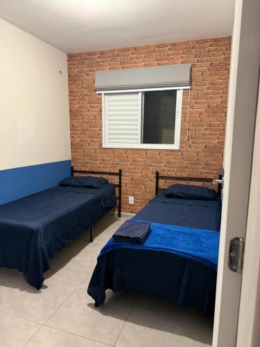 two beds in a room with a brick wall at Apartamento Parque Trianon Exclusive in Araçatuba