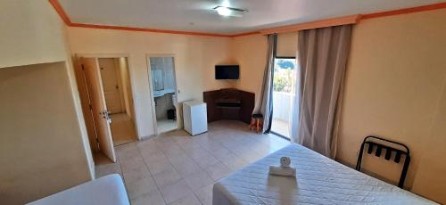 a bedroom with a bed and a room with a desk at Canto do Atlântico Hotel in Guarujá