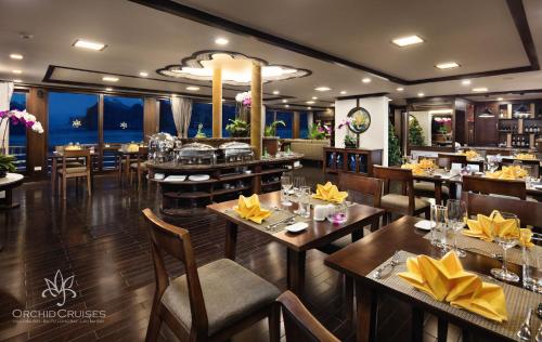 a restaurant with wooden tables and chairs and a dining room at Orchid Classic Cruise in Ha Long