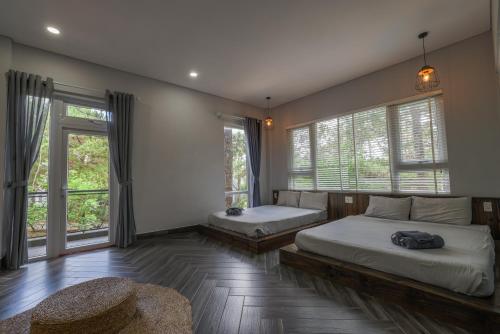 a bedroom with two beds with windows and a table at AP HOME - Lakeside in Ấp Ðinh An (1)