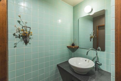 a blue tiled bathroom with a sink and a mirror at Konrai Hotel Matsumoto in Matsumoto