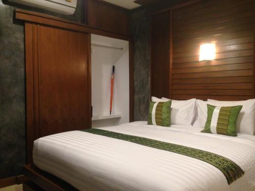 a bedroom with a large white bed with green pillows at BaanPhong Lanta in Ko Lanta