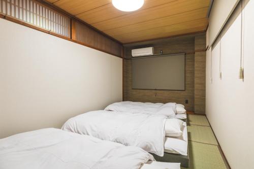 a room with four beds and a projection screen at Konrai Hotel Matsumoto in Matsumoto