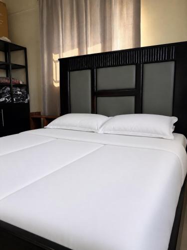a white bed with a black headboard in a room at Home23 Apartments in Jinja