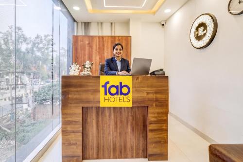 a woman standing at a reception desk with a laptop at FabHotel The Elegant - 150 Meters From Delhi Public School Meerut in Anūpnagar