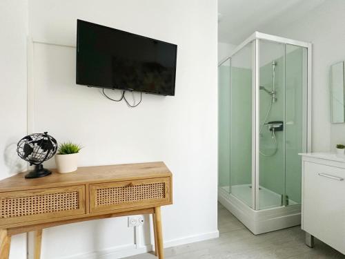 a bathroom with a shower and a television on a wall at L'Échappée Croisienne in Croix