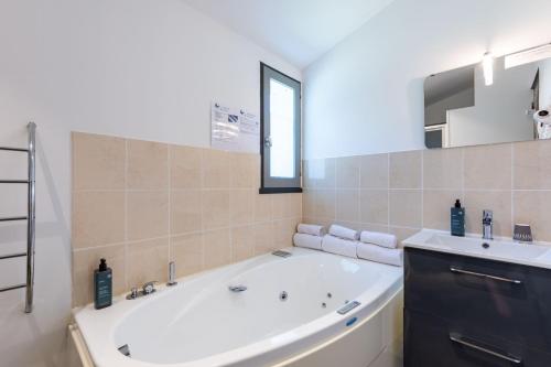 a bathroom with a large tub and a sink at Hôtel Le Parasol in Ars-en-Ré