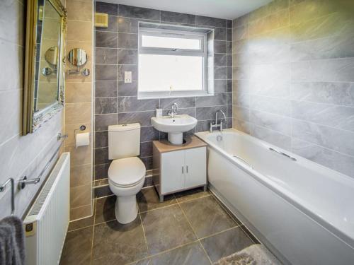 a bathroom with a toilet and a sink and a tub at 4 Bed in Dothan Ty Croes oc-m44701 in Llanfaelog
