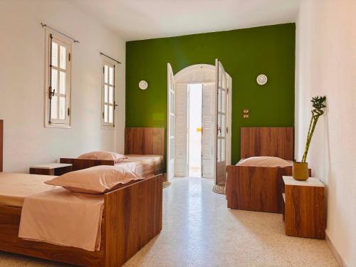 a bedroom with two beds and a green wall at Wostel Djerba Downtown in Houmt Souk