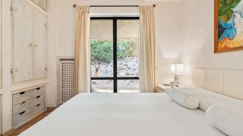a white bedroom with a bed and a window at VILLA ALTHAEA 6, Emma Villas in Orbetello