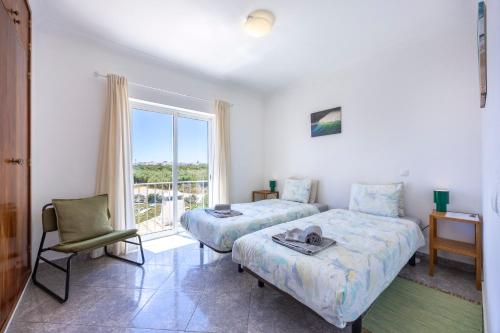 a bedroom with a bed and a chair and a window at Local Guesthouse in Sagres