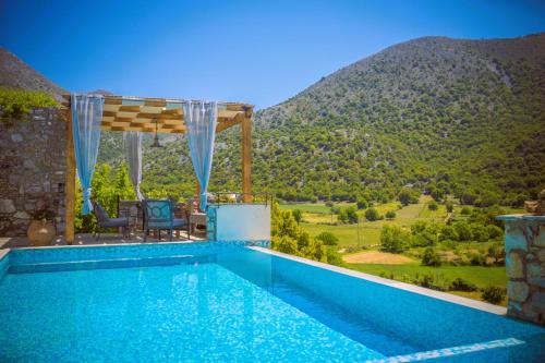 a swimming pool with a mountain in the background at Traditional Villas Askyfou in Karés