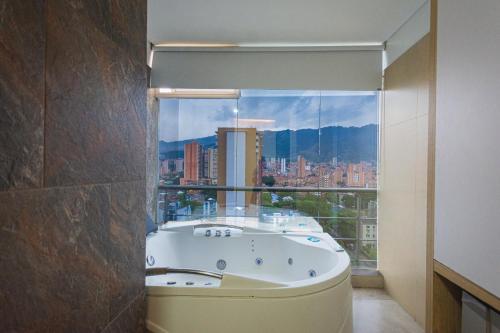 a bathroom with a bath tub with a large window at Hotel Piso 12 in Bello