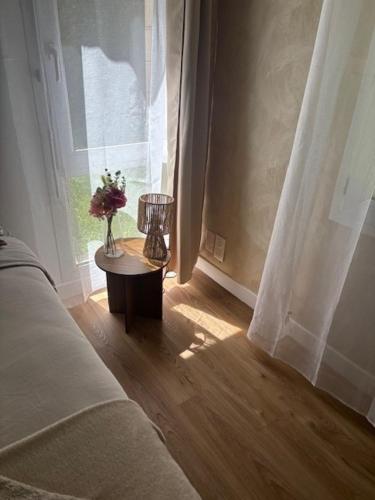 a room with a couch and a table with a vase of flowers at Appartement proche Université Arras, parking gratuit et privé in Arras