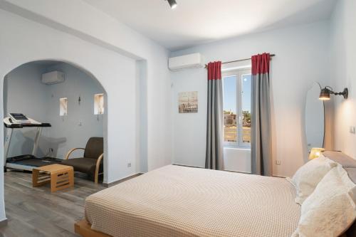 a bedroom with a bed and a chair and a window at Villa Fotis in Ano Syros