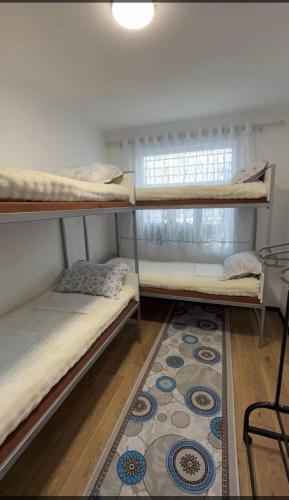 a room with three bunk beds and a rug at Janai Guest house in Karakol