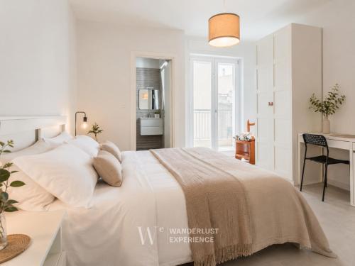 a white bedroom with a large bed and a desk at Wanderlust Experience Pumetta Apartment in Bitonto