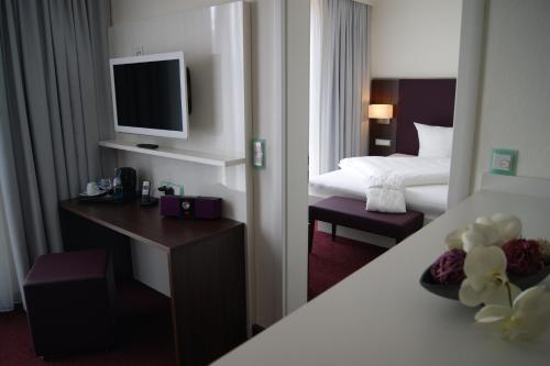 a hotel room with a bed and a desk with a television at Hotel Jungstil in Darmstadt