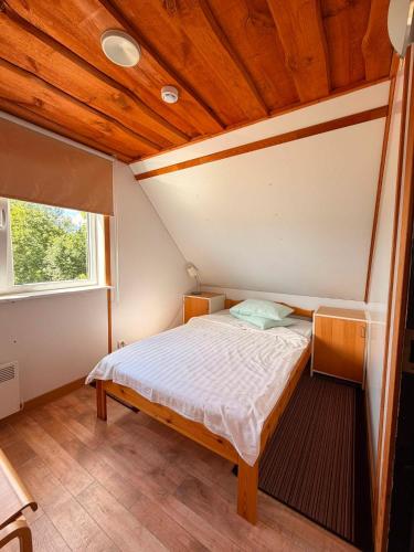 a bed in a room with a wooden ceiling at Privaatne liivarand, saun ja kümblustünn - Pusi Puhkemaja Peipsi ääres in Pusi
