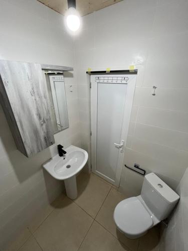 a white bathroom with a toilet and a sink at Leo Guesthouse in Dolasvip'i
