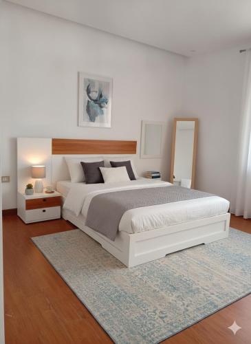 a white bedroom with a large bed and a mirror at 19&G Apt in Addis Ababa