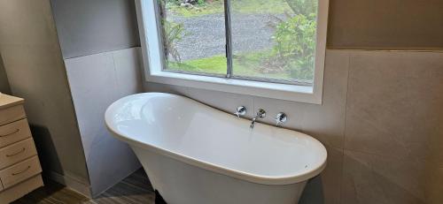 a white bath tub in a bathroom with a window at Cradle Alpine Retreat in Moina