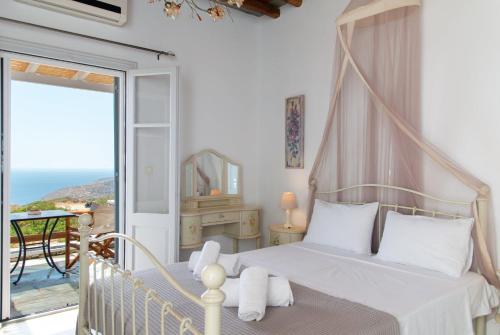 a bedroom with a canopy bed and a balcony at Studios Poulati in Artemonas