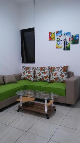a living room with a green couch and a table at Cozy Residence Muwardi in Jakarta