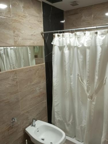 a bathroom with a white shower curtain and a sink at Edificio Leonardo Premium Centro Las Heras in Villa Carlos Paz