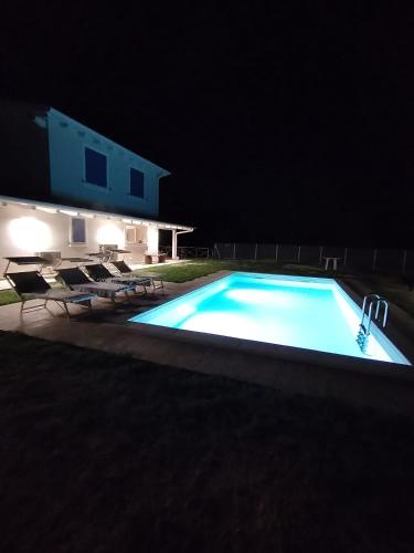 ein Schwimmbad bei Nacht mit Stühlen und einem Haus in der Unterkunft B&bo in Pesaro