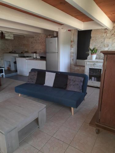 a living room with a blue couch and a kitchen at Maison Vacances in Saint-Savinien
